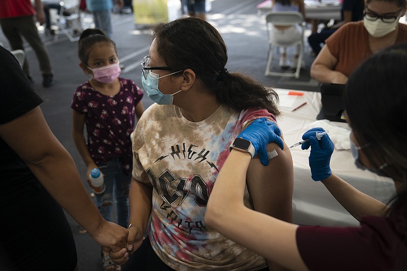 FILE - Holding her mother's hand, Brianna Vivar, 14, looks away while receiving the Pfizer COVID-19 vaccine from pharmacy technician Mary Tran at a vaccine clinic set up in the parking lot of CalOptima, Saturday, Aug. 28, 2021, in Orange, Calif. The U.S. death toll from COVID-19 has hit 1 million, less than 2 1/2 years into the outbreak. (AP Photo/Jae C. Hong, File)