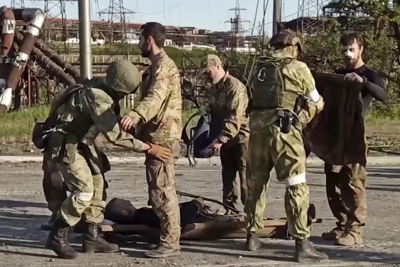 In this photo taken from video released by the Russian Defense Ministry Press Service on Tuesday, May 17, 2022, shows Russian servicemen frisk Ukrainian servicemen as they are being evacuated from the besieged Azovstal steel plant in Mariupol, Ukraine. More than 260 fighters, some severely wounded, were pulled from a steel plant on Monday that is the last redoubt of Ukrainian fighters in the city and transported to two towns controlled by separatists, officials on both sides said. (Russian Defense Ministry Press Service via AP)