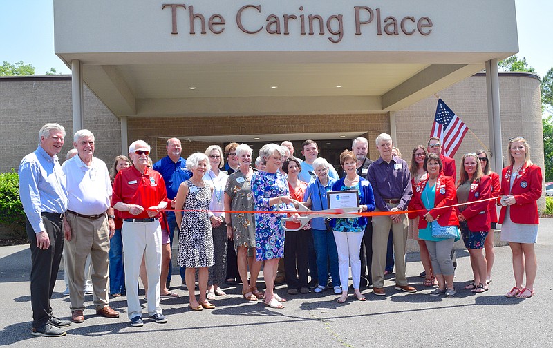 Nina Alter, director of The Caring Place, stands with board members of The Caring Place and members of The Greater Hot Springs Chamber of Commerce as she cuts the ribbon during the facility’s grand re-opening ceremony. – Photo by Donald Cross of The Sentinel-Record