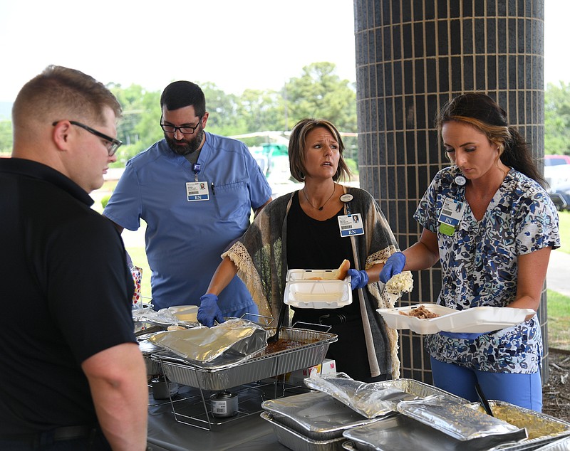 Back, from left, Phillip Nahas, clinical supervisor of the Emergency Department, Renee Fechuch, clinical director, Kayla Bullard, Emergency Department nurse manager, serve lunch to an EMS worker at CHI St. Vincent. - Photo by Tanner Newton of The Sentinel-Record
