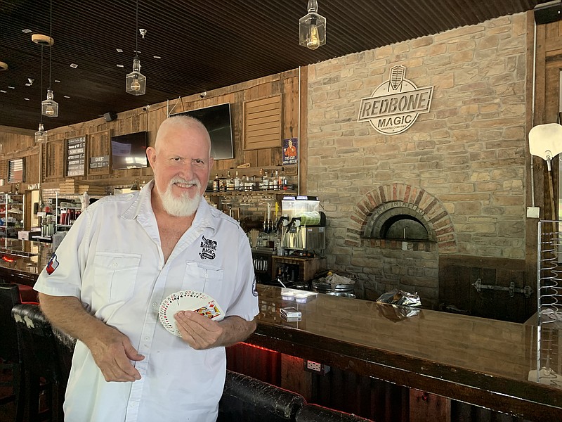 Roger Sheppard stands in front of the bar holding a deck of cards on Tuesday, May 17, 2022, at Redbone Magic Brewery in Texarkana, Texas. (Staff Photo by Mallory Wyatt)
