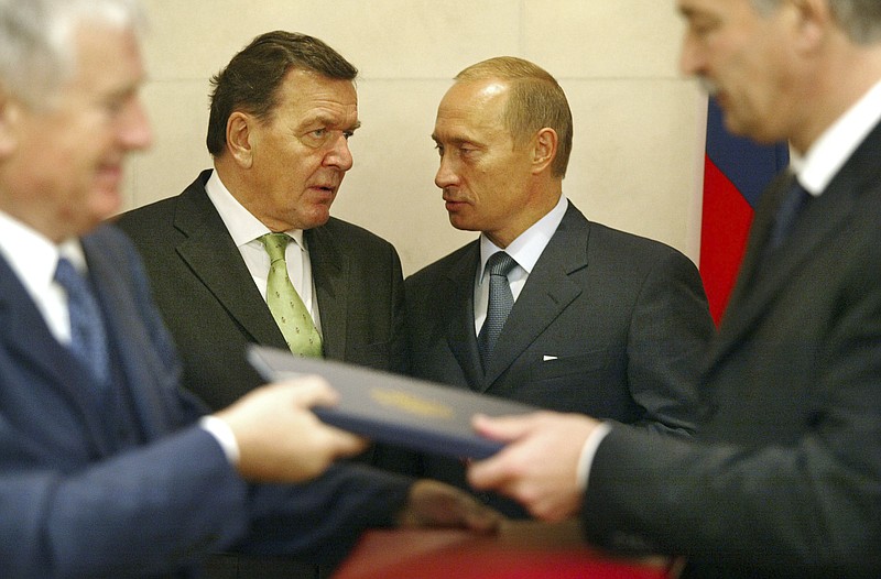 FILE - Russian President Vladimir Putin, background left, and German Chancellor Gerhard Schroeder talks when German Interior Minister Otto Schily and his Russian counterpart Boris Gryslow overhand a contract about travel easement in Yekaterinburg, Oct. 9, 2003. Germany's three governing parties plan to strip former Chancellor Gerhard Schroeder of his office and staff after he maintained and defended his long-standing ties with Russia despite the war in Ukraine. (AP Photo/Markus Schreiber)