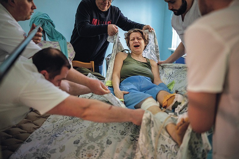 Olena Viter, 45, is transferred to a stretcher before being taken to the operating theatre to undergo further surgery, at a public hospital in Kyiv, Ukraine, Tuesday, May 10, 2022. The explosion that took Olena Viter's left leg also took her son, 14-year-old Ivan, a budding musician already playing in a small orchestra. Her husband Volodymyr buried him and another boy killed in the same blast under a guelder-rose bush in their garden. (AP Photo/Emilio Morenatti)