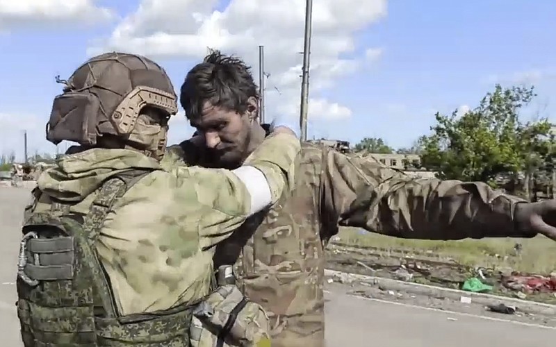 In this photo taken from video released by the Russian Defense Ministry on Friday, May 20, 2022, a Russian serviceman frisks a Ukrainian serviceman after they leaved the besieged Azovstal steel plant in Mariupol, in territory under the government of the Donetsk People's Republic, eastern Ukraine. (Russian Defense Ministry Press Service via AP)