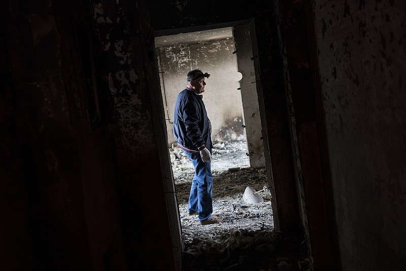 Serhii Klochko, 54, inspects his neighbor's apartment that was damaged during shelling in Kharkiv, eastern Ukraine, Saturday, May 21, 2022. (AP Photo/Bernat Armangue)