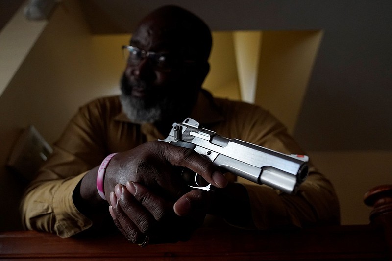 Retired sheriff's deputy Marcus Hargrett poses for a portrait with his pistol Tuesday, Jan. 18, 2022, at his home in Beverly, Ill., home. (AP Photo/Charles Rex Arbogast)
