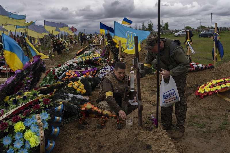 Two national guard visit the grave of a late soldier in Kharkiv cemetery, eastern Ukraine, Sunday, May 22, 2022. (AP Photo/Bernat Armangue)