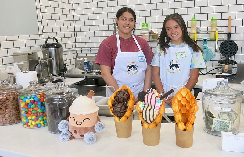 Westside Eagle Observer/SUSAN HOLLAND
Adria Ward and Mikey Larson smile for the camera from behind the counter at Lili's Bubble Waffles on opening day for the business Saturday, May 21, in Gravette. The two served several customers during the grand opening on Saturday. The shop offers bubble waffles, bubble tea and ice cream. Open hours now are 12 noon to 5 p.m. Friday and Saturday only, but plans are to open on other days soon.