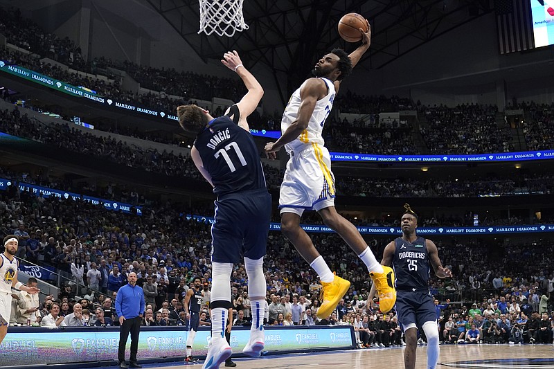 Golden State Warriors forward Andrew Wiggins (22) dunks the ball over Dallas Mavericks guard Luka Doncic (77) during the second half of Game 3 of the NBA basketball playoffs Western Conference finals, Sunday, May 22, 2022, in Dallas. (AP Photo/Tony Gutierrez)