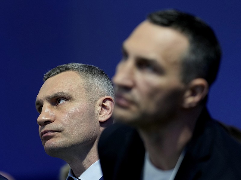 Kyiv Mayor Vitali Klitschko, left, and his brother Wladimir listen toUkrainian President Volodymyr Zelenskyy who is displayed on a screen as he addresses the audience from Kyiv on a screen during the World Economic Forum in Davos, Switzerland, Monday, May 23, 2022. The annual meeting of the World Economic Forum is taking place in Davos from May 22 until May 26, 2022. (AP Photo/Markus Schreiber)