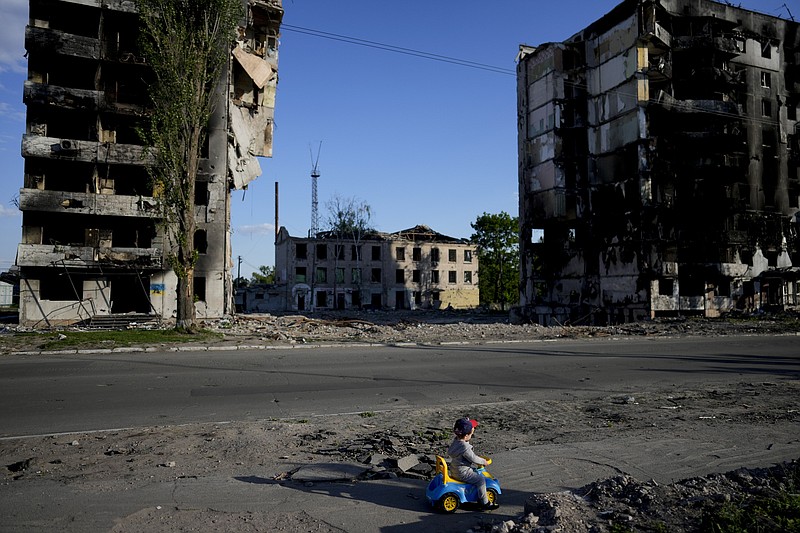A boy plays in front of houses ruined by shelling in Borodyanka, Ukraine, Tuesday, May 24, 2022. (AP Photo/Natacha Pisarenko)