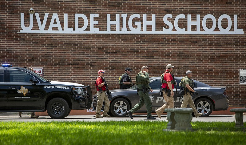 Law enforcement personnel walk outside Uvalde High School after shooting a was reported earlier in the day at Robb Elementary School on Tuesday in Uvalde, Texas. - William Luther/The San Antonio Express-News via AP