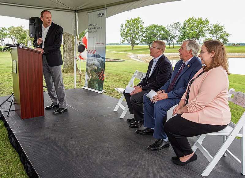 Steve McKinney, left, turns to officials and guests Tuesday, May 24, 2022, during an event to celebrate the 50th anniversary of Hitachi Energy, which originally opened in Jefferson City as Westinghouse in 1972. The company later became ABB and following its most recent sale, is now known as Hitachi. McKinney serves as senior vice president and head of transformers in North America. Seated, from left, are Greg Callahan, Hitachi factory manager; Gov. Mike Parson; and Maggie Kost, acting director of Department of Economic Development. (Julie Smith/News Tribune photo)