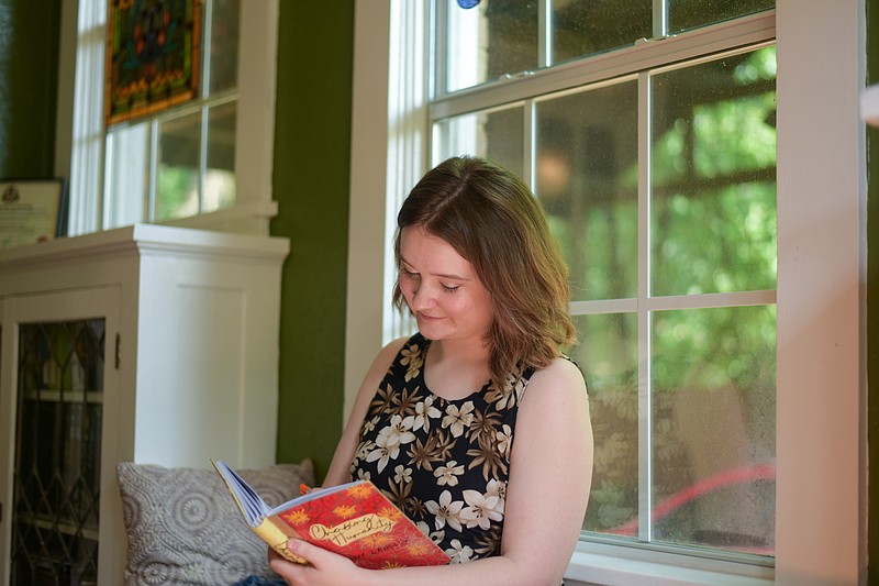 Author Amanda Langley sits in the sunroom of her home Thursday, May 19, 2022, in the historic district of Texarkana, Arkansas, looking through edits of her first novel, "Chasing Humanity." (Staff photo by Erin DeBlanc)