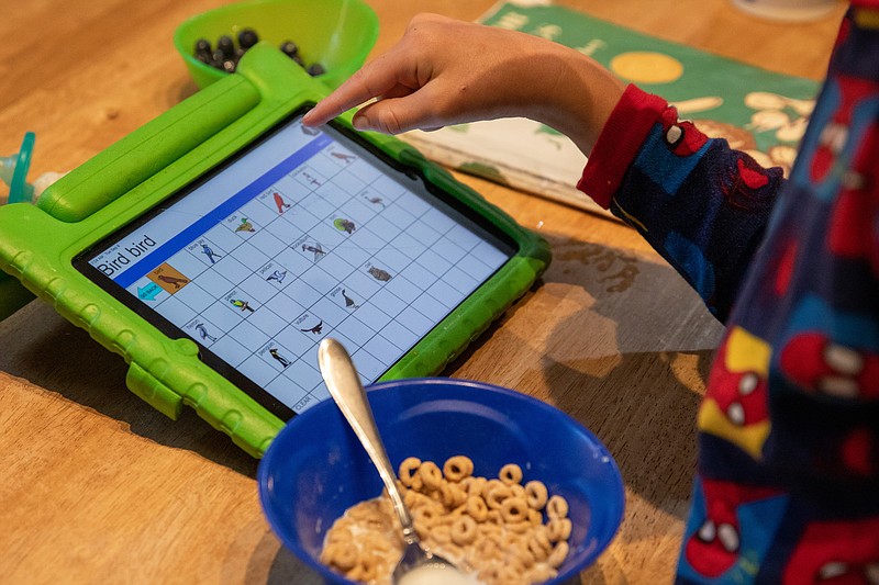 A young boy eats breakfast and works on his electronic tablet on the his first day of school in Arlington, Va., in 2020. (Photo for The Washington Post by Amanda Andrade-Rhoades)