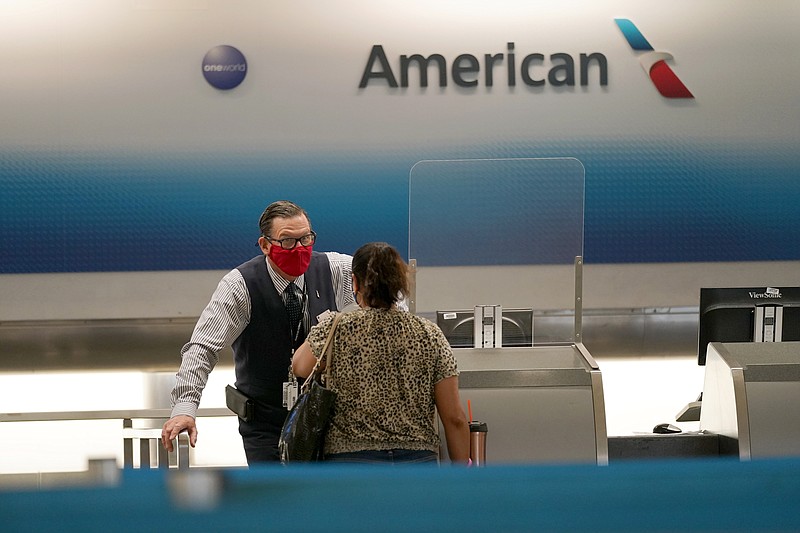 FILE - American Airlines ticket agent Henry Gemdron, left, works with a customer at Miami International Airport in Miami, on Sept. 30, 2020. The Biden administration is siding against the airline industry in a case that involves whether California-based flight crews should get the rest breaks that are required under state law. The airlines say they should not — that only the federal government can regulate the airline industry. On Wednesday, May 25, 2022 the Biden administration asked the U.S. Supreme Court to let the California law stand or send the matter back to lower courts for more consideration. (AP Photo/Lynne Sladky, File)