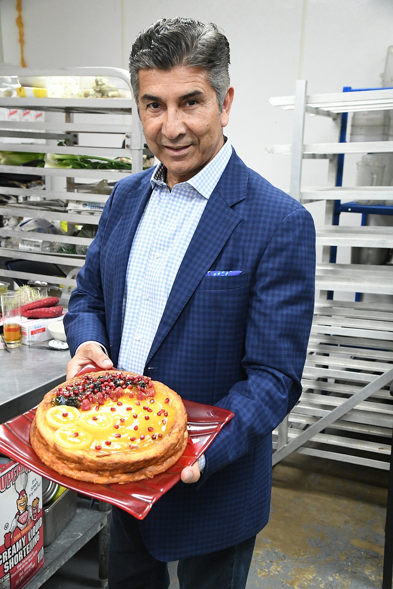 Saddiq Mir, new co-owner, holds a desert in the kitchen. - Photo by Tanner Newton of The Sentinel-Record