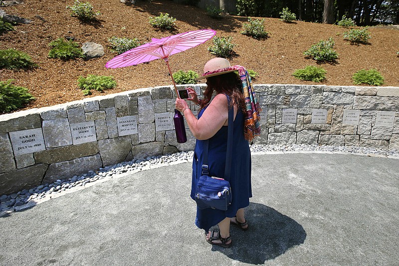 FILE - Karla Hailer, a fifth-grade teacher from Scituate, Mass., takes a video on July 19, 2017, where a memorial stands at the site in Salem, Mass., where five women were hanged as witches more than three centuries years earlier. Massachusetts lawmakers on Thursday, May 26, 2022, formally exonerated Elizabeth Johnson Jr., clearing her name 329 years after she was convicted of witchcraft in 1693 at the height of the Salem Witch Trials. (AP Photo/Stephan Savoia, File)