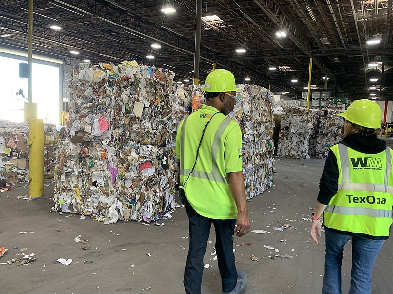 Operations Manager Calvin Poole and Senior Manager of Public Affairs Greta Calvery walk past baled materials Friday, May 27, 2022, at Waste Management's Single Stream Materials Recovery Facility in Arlington, Texas. (Staff photo by Mallory Wyatt)