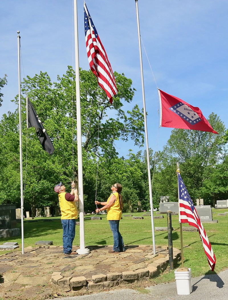 Westside Eagle Observer/SUSAN HOLLAND
American Legion members Chad Young and his wife, Anita Young, raise the flag of the United States of America at the Memorial Day service at Hillcrest Cemetery. Chad and Anita recently became members of the John E. Tracy Legion post at Gravette after the post at Southwest City, Mo., was disbanded.