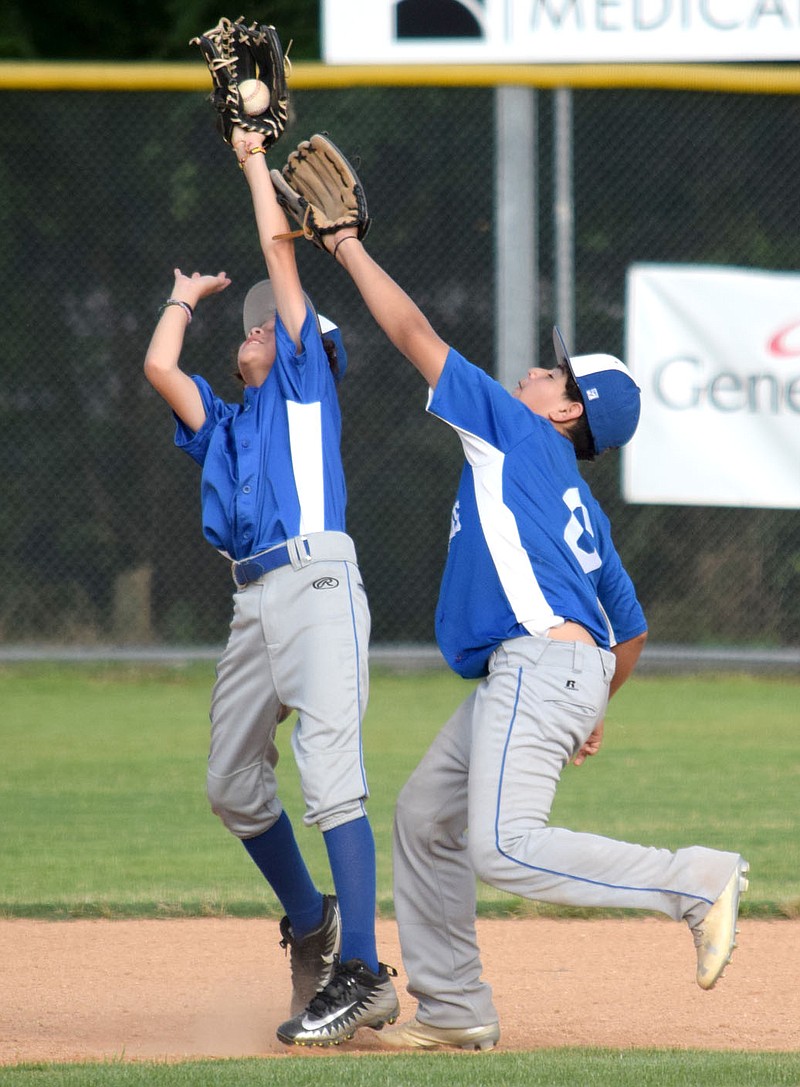 Westside Eagle Observer/MIKE ECKELS
Brain Thor (left) and Marlon Revolorio go after a pop up fly ball during the May 31 Babe Ruth youth baseball game between Siloam Springs A and Decatur at James Butts Baseball Complex in Siloam Springs. It was Thor who made the catch for the first out in the top of the second inning.