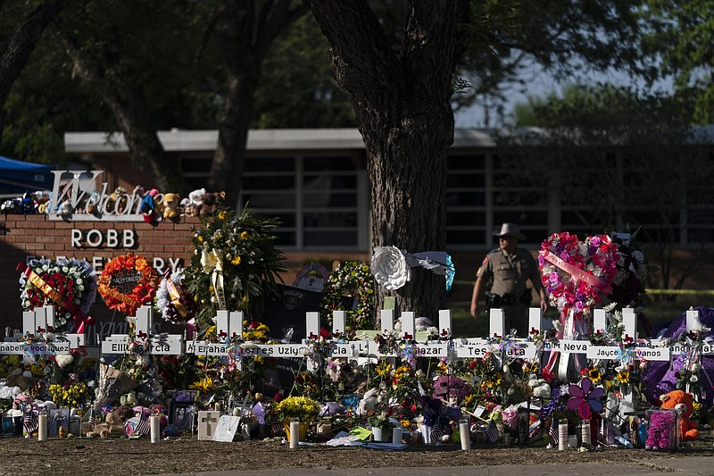 FILE - Flowers and candles are placed around crosses at a memorial outside Robb Elementary School to honor the victims killed in this week's school shooting in Uvalde, Texas Saturday, May 28, 2022. The gunmen in two of the nation's most recent mass shootings, including last week's massacre at the Texas elementary school, legally bought the assault weapons they used after they turned 18. That's prompting Congress and policymakers in even the reddest of states to revisit whether to raise the age limit to purchase such weapons.  (AP Photo/Jae C. Hong, File)