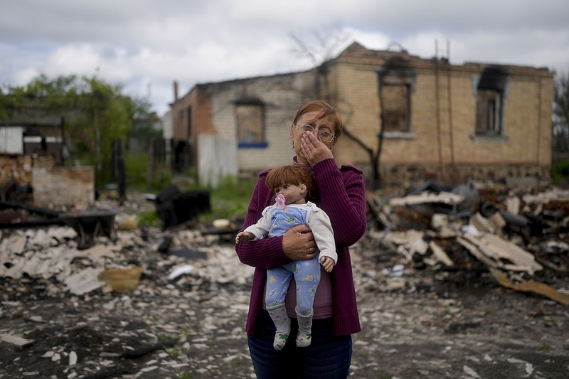 Nila Zelinska holds a doll belonging to her granddaughter, she was able to find in her destroyed house in Potashnya outskirts Kyiv, Ukraine, Tuesday, May 31, 2022. Zelinska just returned to her home town after escaping war to find out she is homeless. (AP Photo/Natacha Pisarenko)