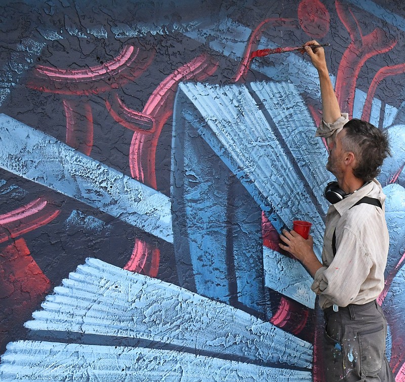 Jason Botkin paints a mural at Central Theatre. - Photo by Tanner Newton of The Sentinel-Record