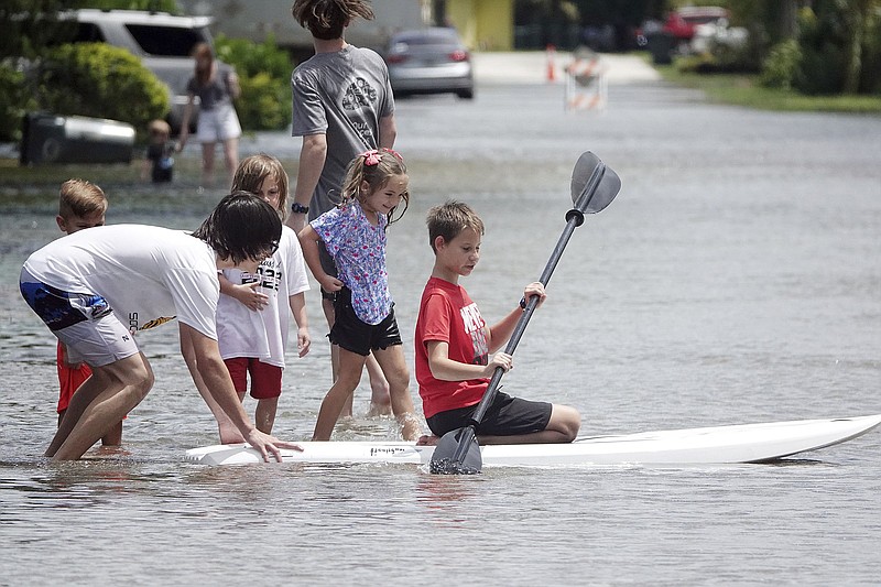 Kyle Hilderbrandt, right, paddles on NE 2nd Ave., in Oakland Park, Fla., Saturday, June 4, 2022. Tropical weather brought heavy rain and flooding to South Florida. (Joe Cavaretta/South Florida Sun-Sentinel via AP)