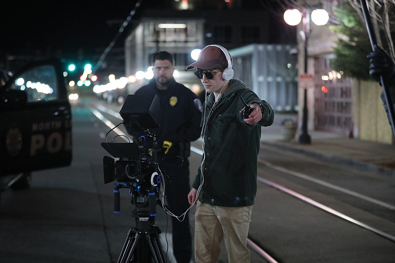 Corbin Pitts filmed a car chase scene for his film “Salad Days” in North Little Rock’s Argenta district, shutting down the street. Keeping an eye on Pitts is North Little Rock police detective Raul Dallas. (Special to the Democrat-Gazette/Warren McCullough)