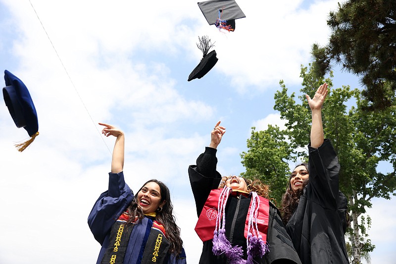 Cindy, Cecilia and Abigail Escobedo, from left, throw their caps into the air while posing for a portrait wearing their graduation outfits at their home on the Sunday, May 22, 2022, in Covina, California. (Dania Maxwell/Los Angeles Times/TNS)