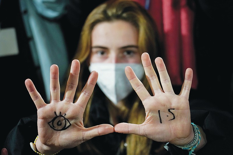 FILE - A youngster, with an eye drawn on her hand to show she is watching and 1.5 for countries to keep warming below 1.5 degrees Celsius, takes part in a Fridays for Future climate protest inside a plenary corridor at the SEC (Scottish Event Campus) venue for the COP26 U.N. Climate Summit, in Glasgow, Scotland, Nov. 10, 2021. The idea of tinkering with the air to cool Earth's ever-warming climate seems to be gaining momentum. Two new high-powered panels have started to look at the ethics and governing rules surrounding the controversial technologies of geoengineering. (AP Photo/Alberto Pezzali, File)