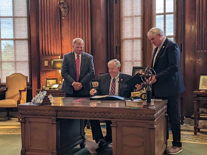 Bill sponsors Rep. Barry Hovis and Sen. Jason Bean flanked Missouri Gov. Mike Parson Tuesday, June 7, 2022, as he signed SB 987, a bill expanding permissions for river gambling facilities. Parson signed seven bills into law on Tuesday. (Ryan Pivoney/News Tribune photo)