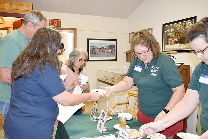 Rachel Dickerson/The Weekly Vista Renee Mickelson (left) accepts a plate of jams and jellies from Bella Vista Historic Museum volunteer Wendy Hughes at the historic foods tasting on Saturday.