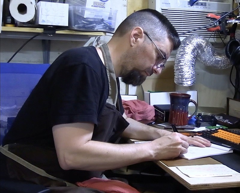 Shawn Newton writes with one of his handmade fountain pens. – Photo by Courtney Edwards of The Sentinel-Record.