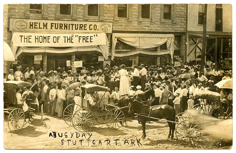 Stuttgart, 1911: “This will show you we are still doing business in Stuttgart; I was out the other morning and killed 35 squirrels before noon.” Helm Furniture was showing a new product in the street, perhaps a stove or sewing machine. The slogan was “Home of the ‘free’” with “free” in qualifying quotations. Helm, per the sign, was an undertaker and embalmer and sold furniture and rugs.
Arkansas Postcard Past, P.O. Box 2221, Little Rock, AR 72203