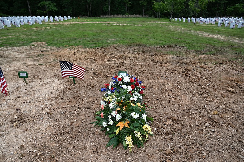 Flowers lie over the top of a grave adorned by a temporary grave marker at the Arkansas State Veterans Cemetery in North Little Rock on Thursday, May 26, 2022.
(Arkansas Democrat-Gazette/Stephen Swofford)