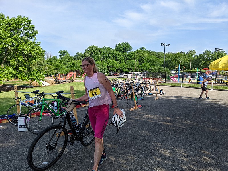 Lisa Dyer, 57, of Jefferson City, stores her bike before transitioning to the sprinting leg of the Jefferson City Triathlon on Sunday, June 12, 2022. Dyer coaches the Jefferson City YMCA Barracuda Swim Team, one of the programs that benefits from proceeds the annual swimming, biking and running race generate. She finished third in her age group. (Ryan Pivoney/News Tribune photo)