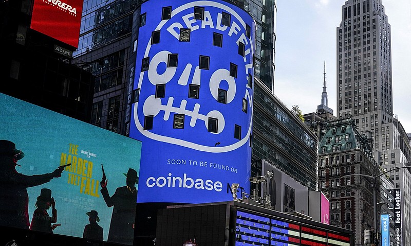 FILE - An advertisement for Coinbase, center, is displayed on NASDAQ billboard in Times Square, New York, Thursday, Nov. 4, 2021. Coinbase Global says, Tuesday, June 14, 2022, it plans to cut about 1,100 jobs, or approximately 18% of its global workforce, as part of a restructuring in order to help manage its operating expenses in response to current market conditions. The company said in a regulatory filing that it expects to have about 5,000 total employees at the end of its current fiscal quarter on June 30. (AP Photo/Seth Wenig, File)
