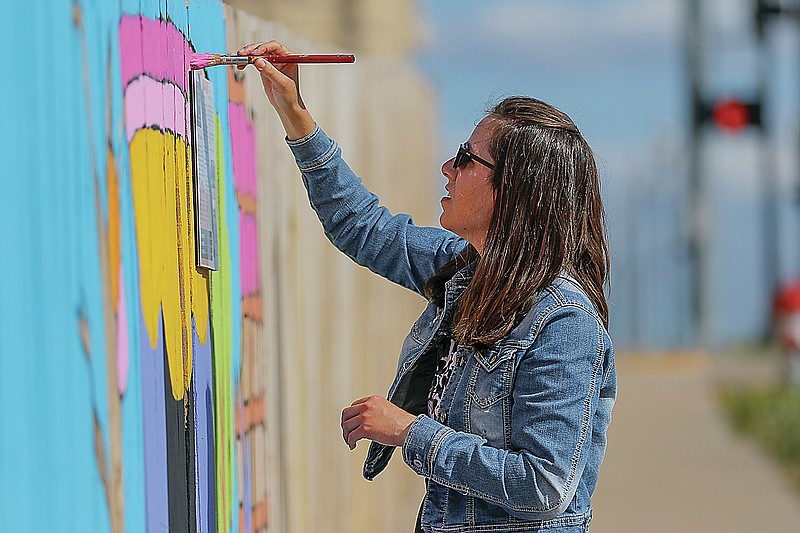 Amy Greenbank continues working on a mural along Capitol Avenue, near Avenue Q, on a sunny and temperate April 2015 afternoon. (Liv Paggiarino/News Tribune file photo)