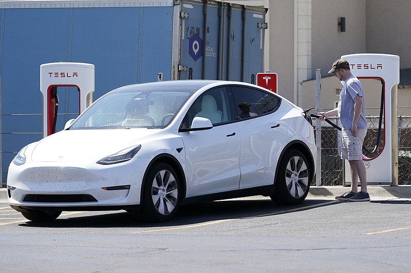 FILE - A Tesla owner charges his vehicle at a charging station in Topeka, Kan., Monday, April 5, 2021.  Tesla reported 273 crashes involving partially automated driving systems, according to statistics released by U.S. safety regulators on Wednesday, June 15, 2022. But the National Highway Traffic Safety Administration cautioned against using the numbers to compare automakers, saying it didn’t weigh them by the number of vehicles from each manufacturer that use the systems, or how many miles those vehicles traveled.  (AP Photo/Orlin Wagner, File)