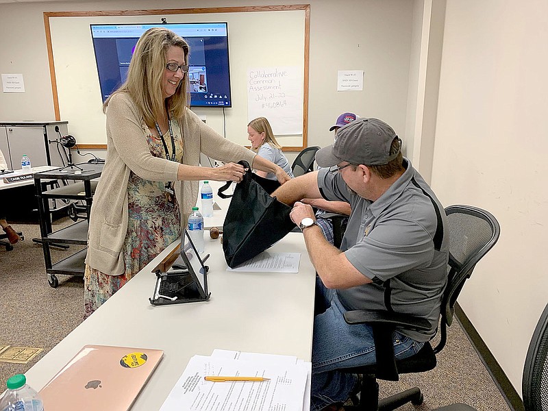 LYNN KUTTER ENTERPRISE-LEADER
Reba Holmes, superintendent of Prairie Grove Schools, holds the bag for school board president William Dick to draw a number for the length of his current term on the board. Dick's term will be four years. He was elected board president at the June 14 meeting, replacing Casie Ruland, who has served as president the past year.