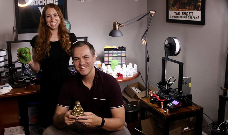 Cameron Gerber/News Tribune
Austin and Stephanie Petersen pose with figures produced by their 3D printer farm.