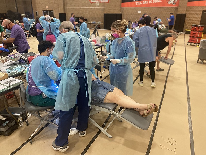 Volunteer dentists work on a patient during the fifth Texas Mission of Mercy Mobile Dental Clinic on Friday, June 17, 2022, at Texas High School. The clinic is designed to provide pain-relieving dental care at no cost to underserved Texarkana-area residents. (Staff photo by Andrew Bell)