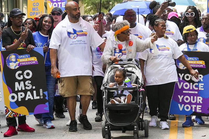 Opal Lee pushes one of her great granddaughters in a stroller as she waves to musicians playing along the route during the 2022 Opal's Walk for Freedom on Saturday, June 18, 2022, in Fort Worth. Lee, often referred to as the "Grandmother of Juneteenth" led her annual two-and-a-half-mile walk, representing the number of years after the Emancipation Proclamation before enslaved people in Texas learned they were free. (Smiley N. Pool/The Dallas Morning News via AP)