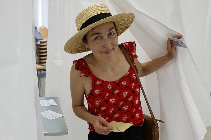 Noemie Rousseau leaves the voting booth in a polling station Sunday, June 19, 2022 in Strasbourg, eastern France. French voters are going to the polls in the final round of key parliamentary elections that will demonstrate how much legroom President Emmanuel Macron's party will be given to implement his ambitious domestic agenda. (AP Photo/Jean-Francois Badias)