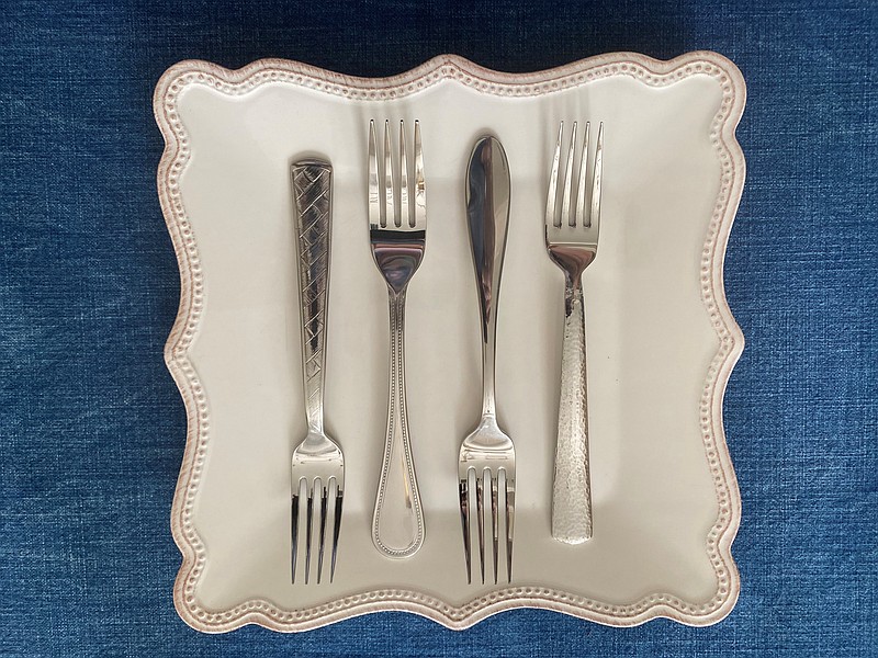 When testing out flatware, be sure to physically handle it, and also see how the pattern gets along with your dishes. Here, the author tests four sample fork patterns before committing. (Courtesy of Marni Jameson)