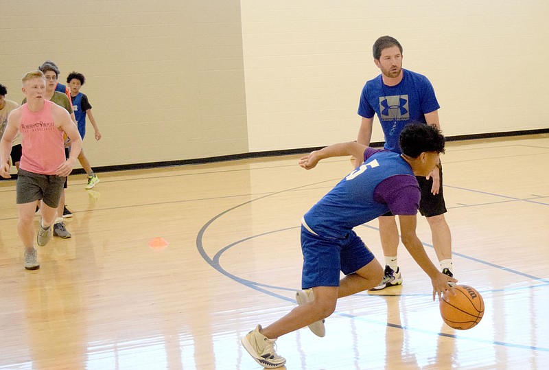 Westside Eagle Observer/MIKE ECKELS Austin Froderking (upper right) studies Brandon Cruz’ technique as he dribbles past the new Decatur boys' head coach during the first junior and senior high boys' practice session in the gym at Decatur Middle School on June 20. Froderking takes the helm from two-year coach Dayton Shaw, who took a similar position in Missouri.