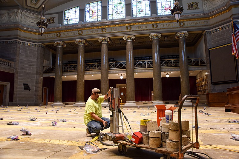 James Rodgers of Concrete Coring and Cutting in Ashland removes a concrete plug from the coring saw Wednesday, June 22, 2022, while cutting holes in the floor of the Missouri House of Representatives floor. Work continues in the chamber where concrete is being cored to allow for flush mounting of electrical and other necessary wiring that goes to representatives' desks. After that work is done and new or additional wiring is run, new wool carpet will be installed. (Julie Smith/News Tribune photo)