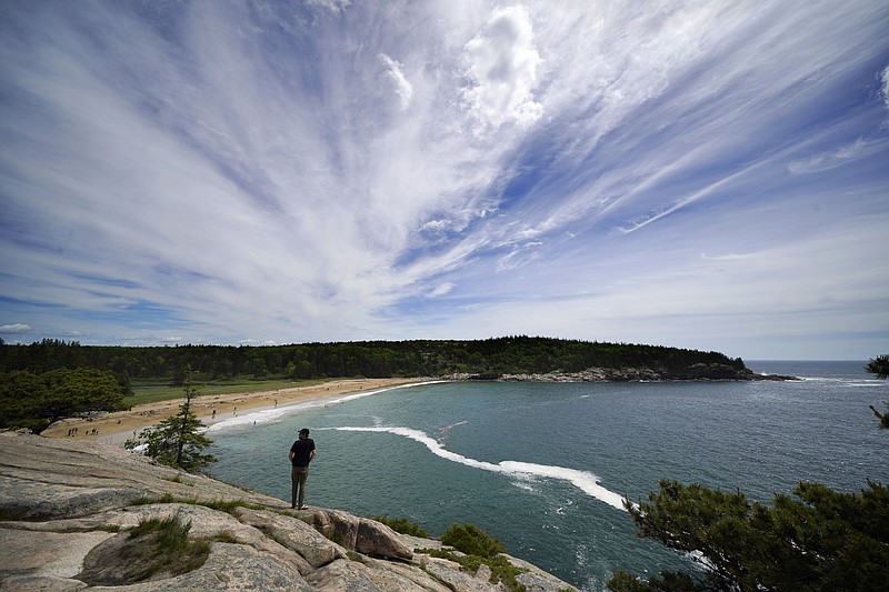 CORRECTS YEAR TO 2022 INSTEAD OF 2002 - A man takes in the view of Sand Beach from a rocky overlook in Acadia National Park, Saturday, June 11, 2022, near Bar Harbor, Maine. The park will not have lifeguards on duty this summer due to worker and housing shortages. (AP Photo/Robert F. Bukaty)